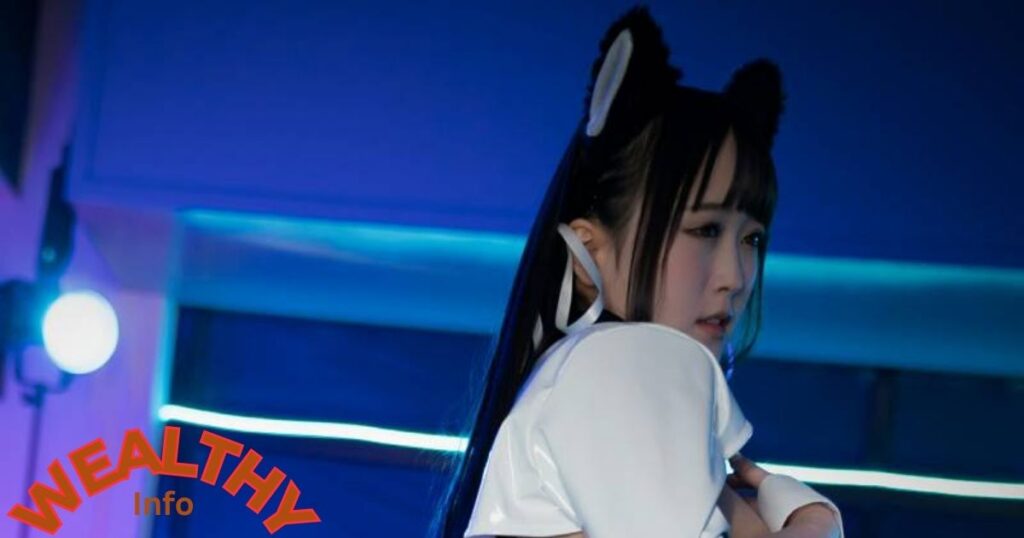 Ria Kurumi in a stylish white outfit during a performance, showcasing her talent and rising net worth.