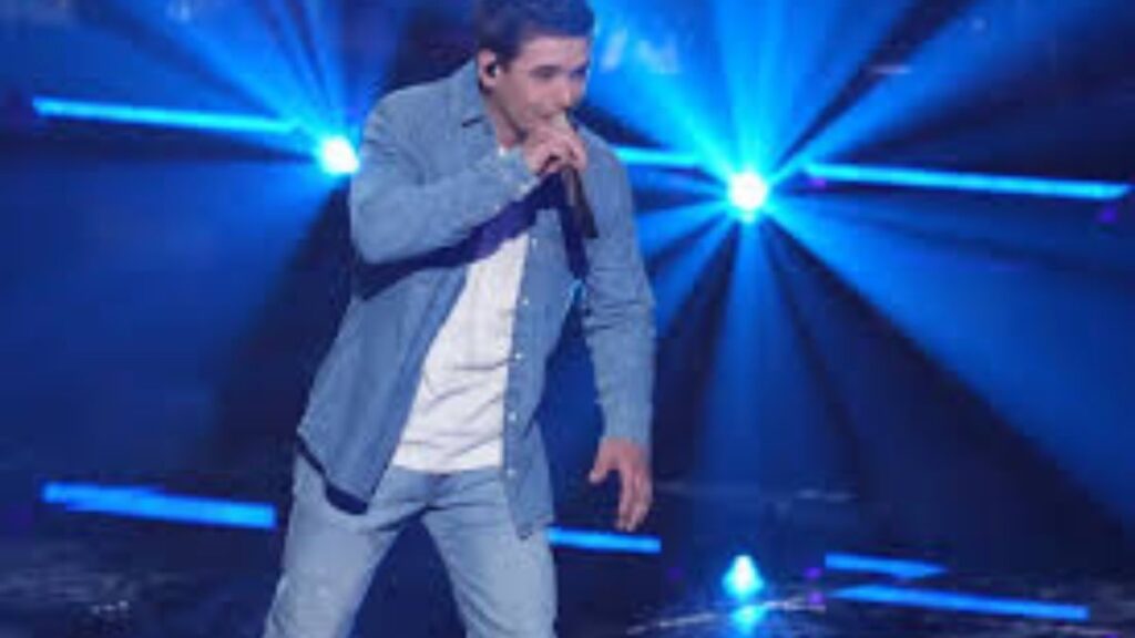 Noah Thompson performing live on stage during his Alabama concert tour with blue lights shining behind him.