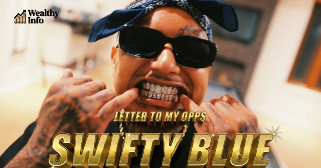 Swifty Blue showing his diamond grillz while wearing sunglasses and a blue bandana – Swifty Blue net worth